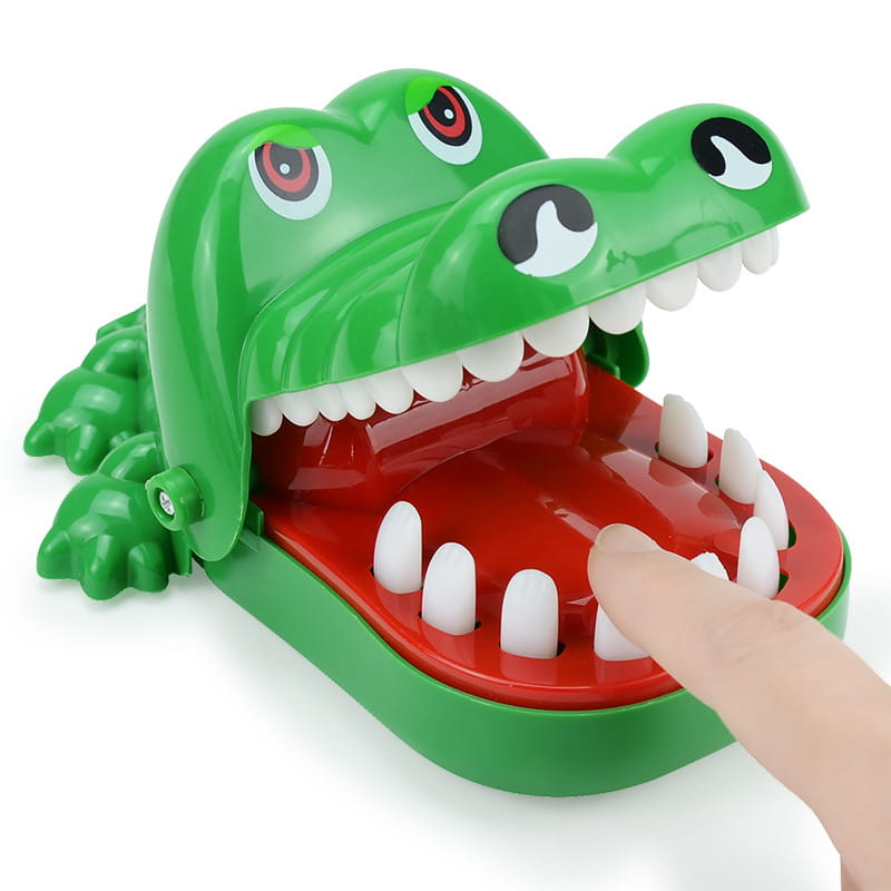 green plastic crocodile biting finger game interactive kids toy with red interior white teeth cartoon eyes and a finger inserted into its mouth
