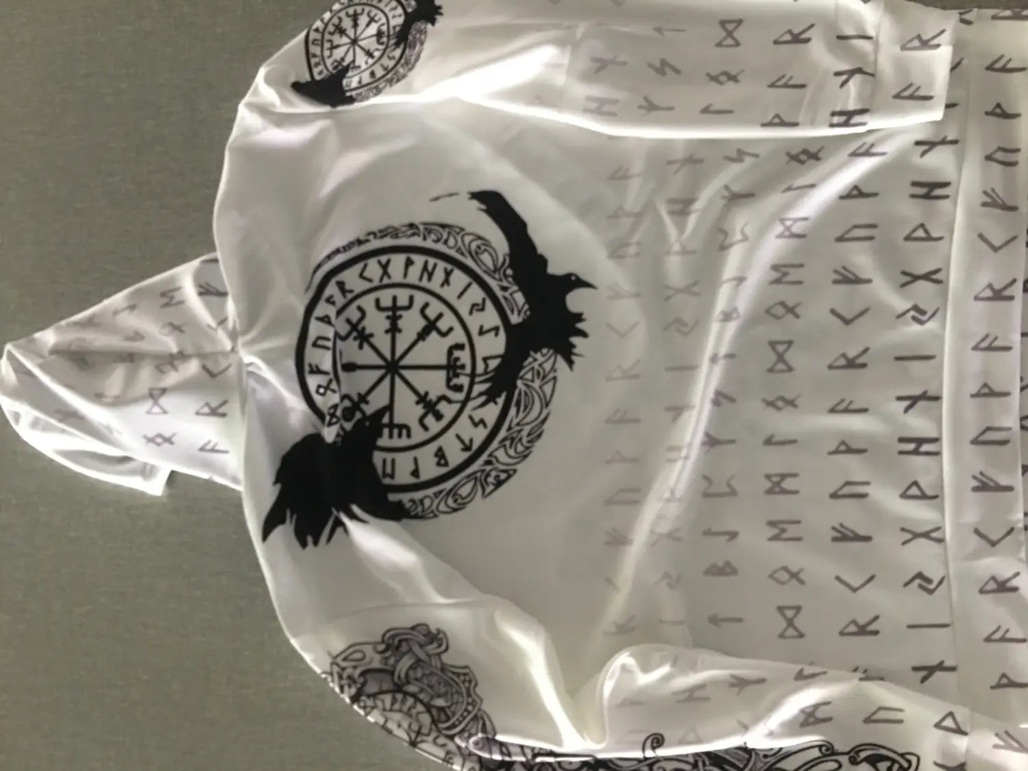 White satin-like fabric shirt featuring black Viking runes and a central circular design with two ravens in the Valknut Norse Graphic 3d Print Zip Up Hoodie.