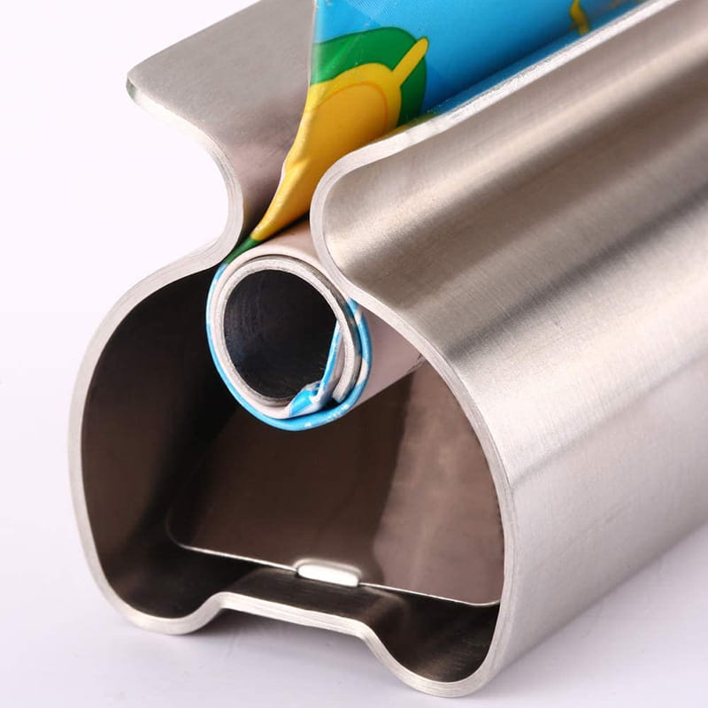 Stainless steel toothpaste squeezer and holder set featuring a sleek curved roll holder design holding a colorful plastic food wrap.