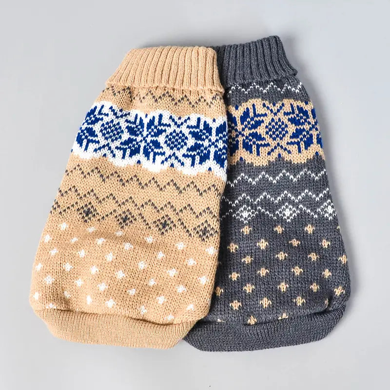 Two knitted dog sweaters in beige with blue and white Nordic snowflake patterns and dark gray with similar designs for winter pet apparel.