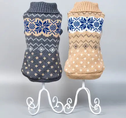 two knitted sweater-style dog vests in dark gray with blue and cream snowflake patterns and beige with navy and white geometric designs for winter pet apparel