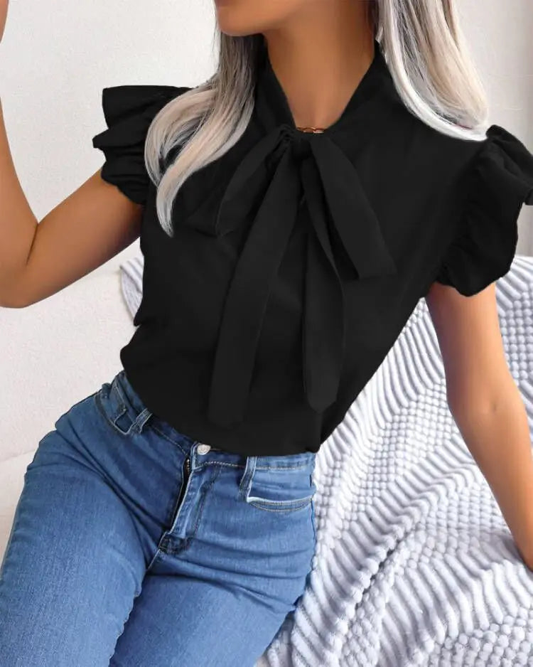 Black ruffled bowknot short sleeve blouse featuring a prominent bow at the neckline and ruffled sleeves.
