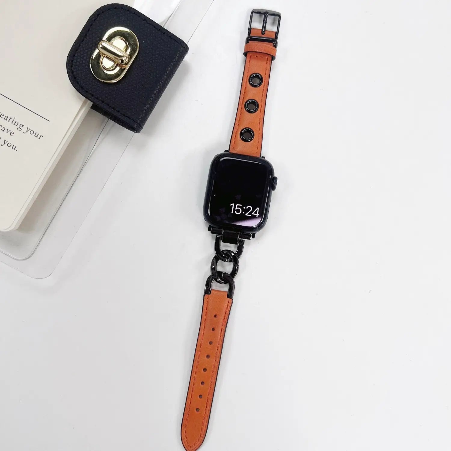 Orange leather Apple Watch band featuring black metal hardware and a retro chain link connector.