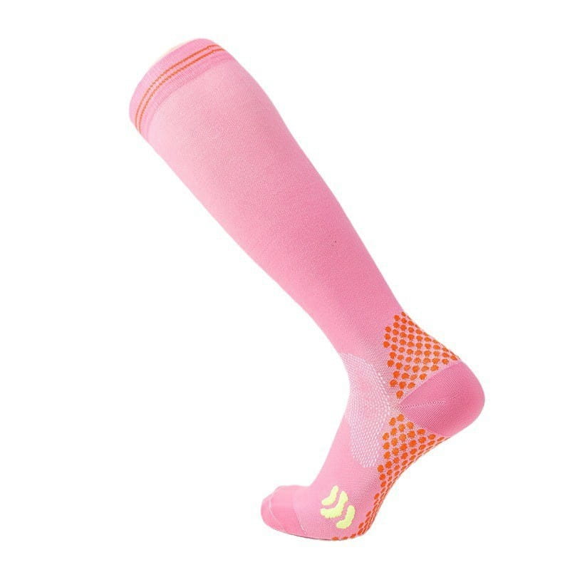 Pink compression soccer socks with orange textured grip dots on the heel and sole and a subtle yellow logo near the toe designed for athletic use.