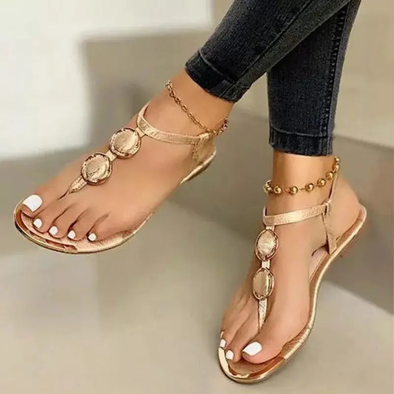 women’s gold-toned flat sandals with decorative metal oval medallions and beaded ankle straps for stylish comfort