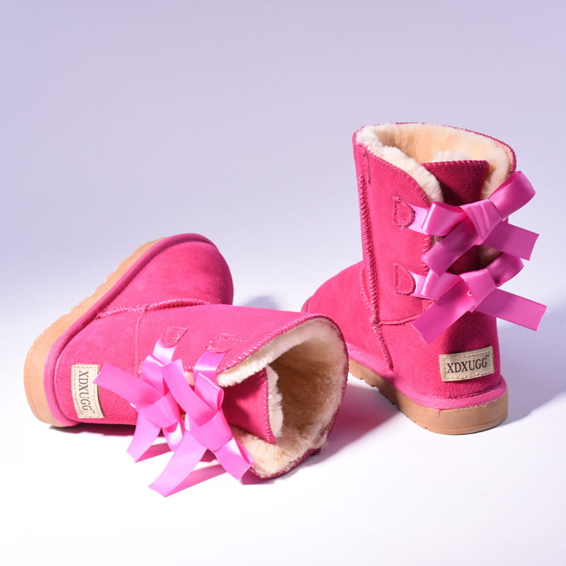Bright pink suede women snow boots with warm plush shearling lining and matching ribbon bows on the back of the ankle boots.