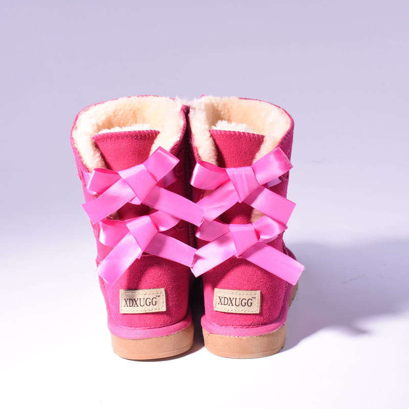 Bright pink suede women snow boots with plush white fur lining and matching satin bows tied across the front for warmth in winter.