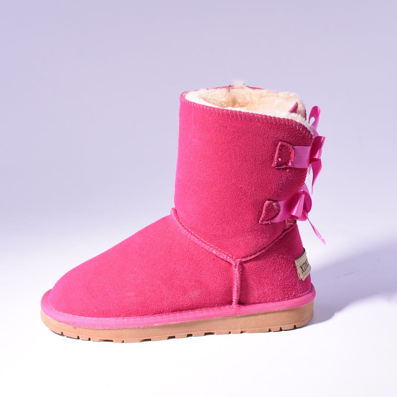 A vibrant pink suede women snow boot featuring warm white shearling lining and decorative matching bows on the side for winter use.