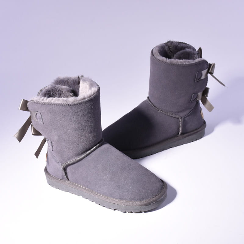 gray suede ugg-style women snow boots with plush gray lining and decorative bows on the back, shown from the back side, designed for warmth in winter conditions.