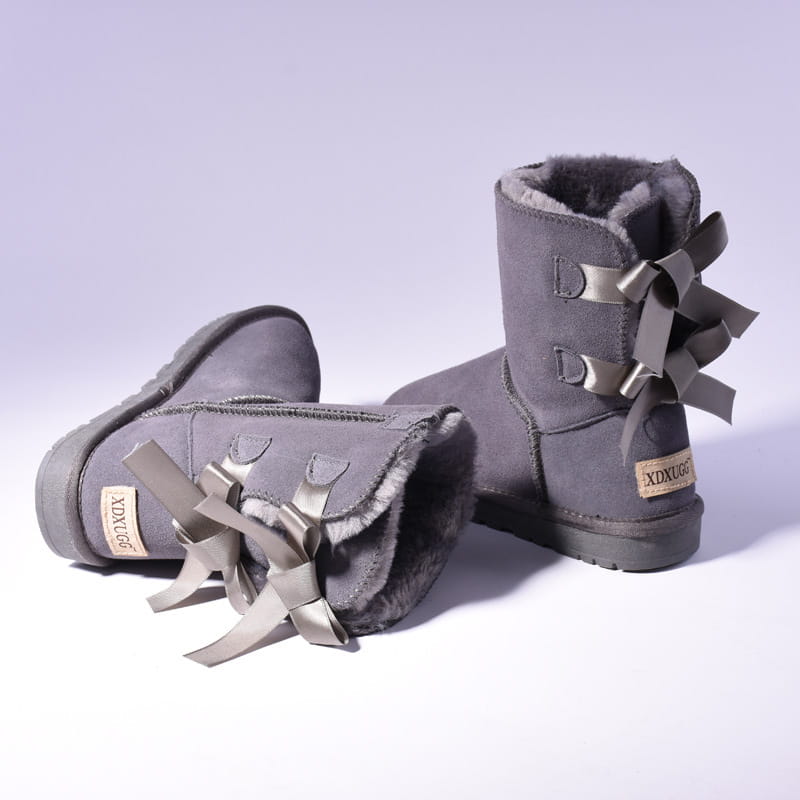Gray suede ugg-style women snow boots with warm plush shearling lining and decorative metallic d-shaped buckles adorned with matching satin bows for winter wear.