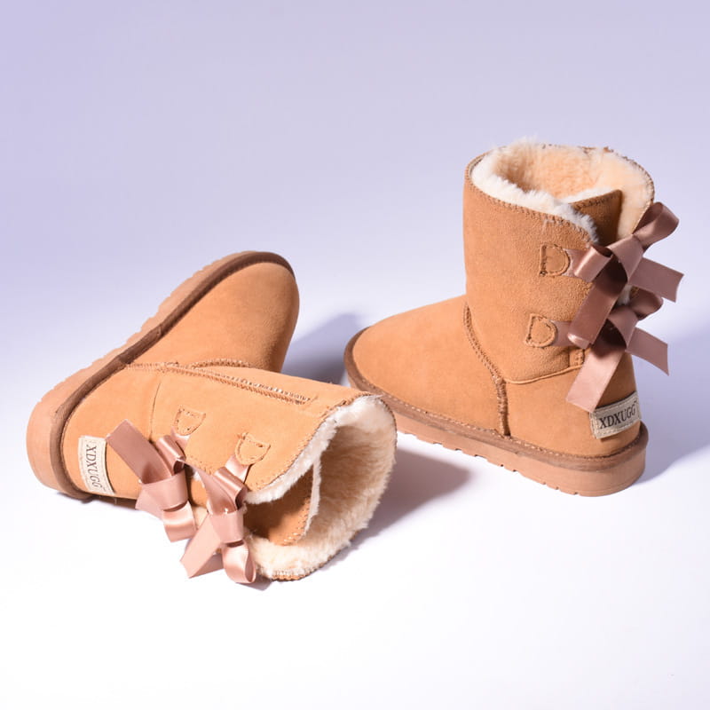 Tan suede women snow boots warm ugg style ankle boots with plush white shearling lining and matching satin bows on the outer side designed for winter.