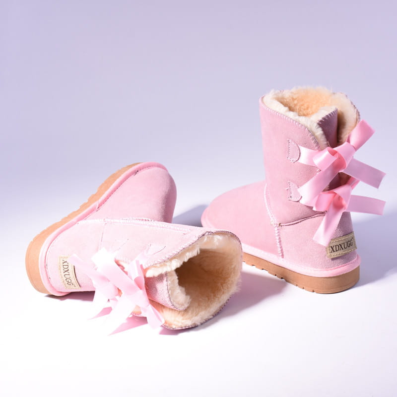 women snow boots in pink suede with fluffy shearling lining and matching pink ribbon bows on the back shown from the back side