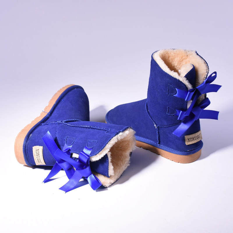 Royal blue suede women snow boots with plush beige fur lining and matching satin bows on the back in an ugg style winter ankle boot design.