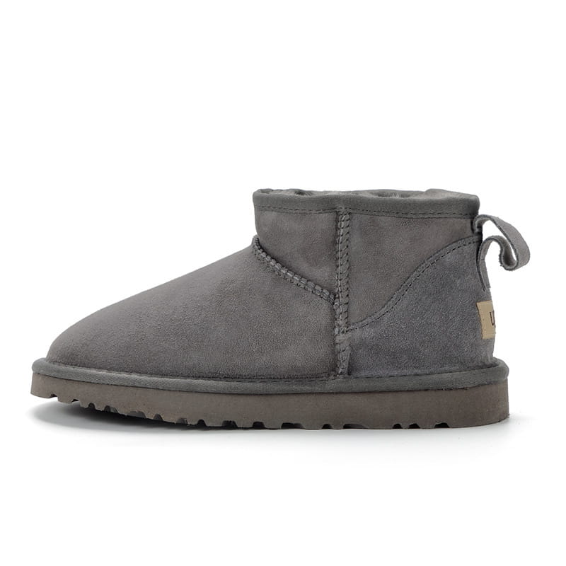 Gray suede sheepskin mini snow boot with plush interior and a pull tab on the back side.