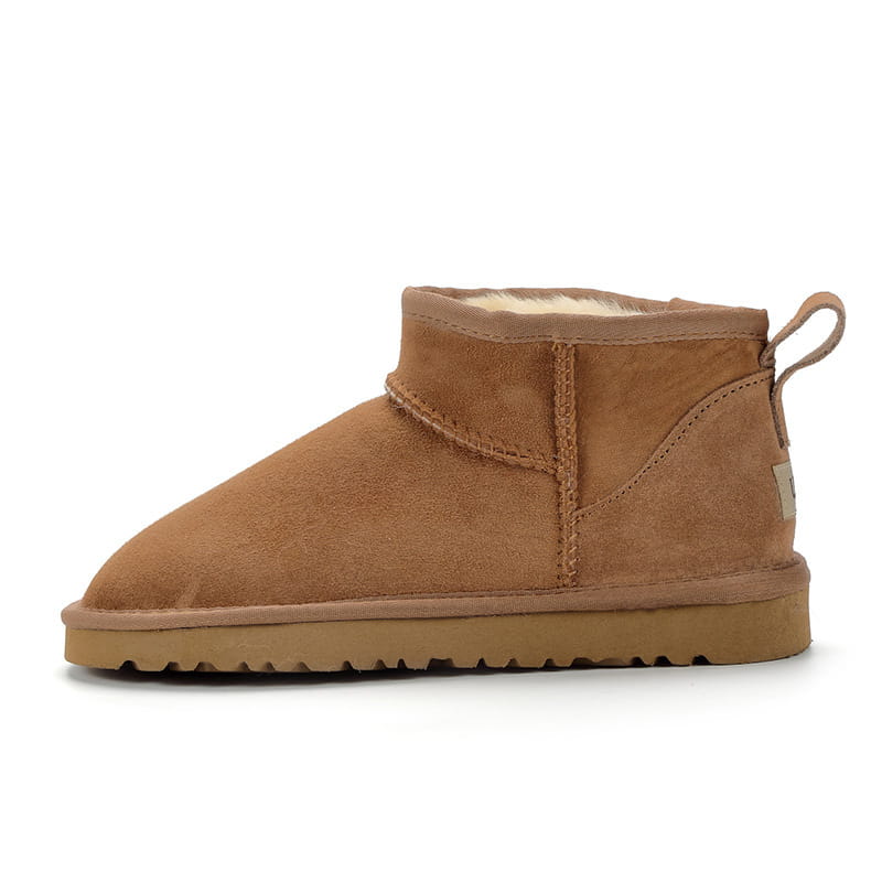 Tan suede sheepskin mini snow boot with plush white shearling lining and rubber sole designed as short ankle footwear.