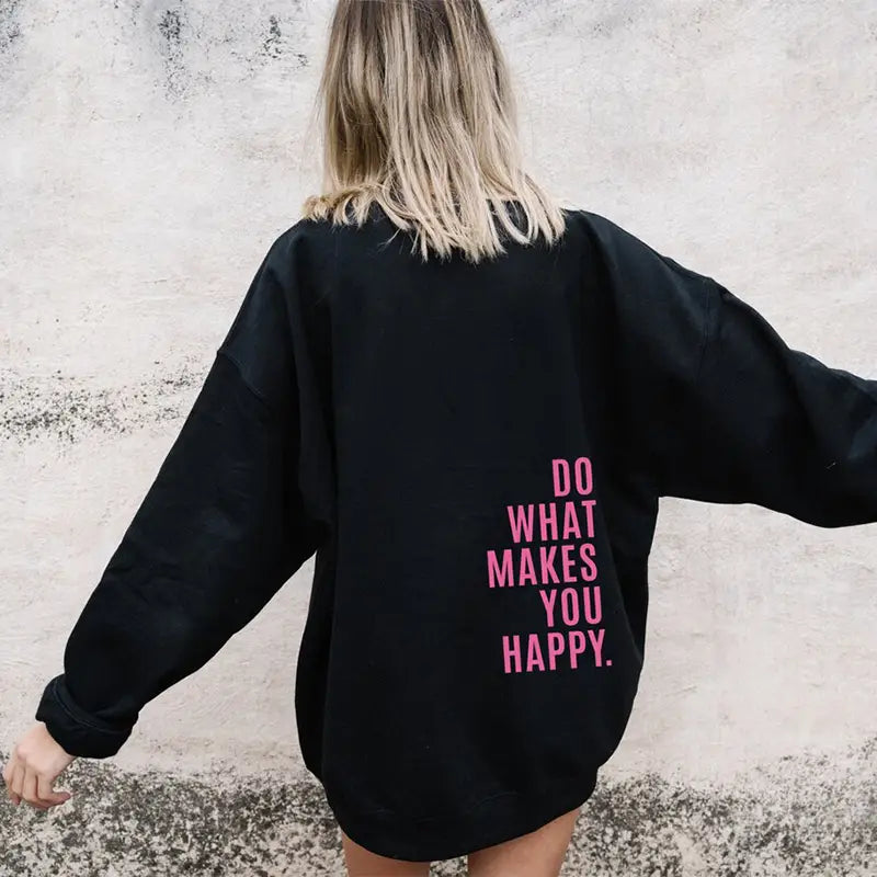 Sweat à capuche streetwear oversize noir avec du texte rose indiquant « do what makes you happy » au dos.