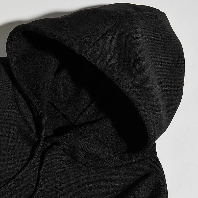 Sweat à capuche noir présentant une matière douce et texturée, ainsi que des cordons assortis, provenant de la collection de sweat à capuche streetwear oversize « Do what makes you Happy ».