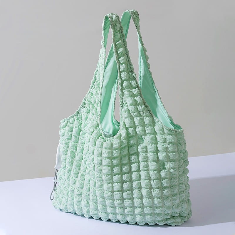 Mint green quilted fabric tote bag with a matching interior lining and textured puffy square pattern designed as a plush animal pet carrier bag backpack.