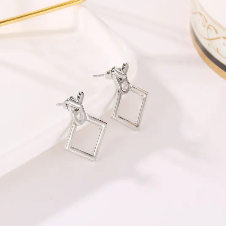 Silberne geometrische Tropfenohrringe mit minimalistischer Quadratfassung und verschlungenem Knotendesign, vorgestellt in der Kollektion der geometrischen Goldpfeil- und hohlen Quadratohrstecker.