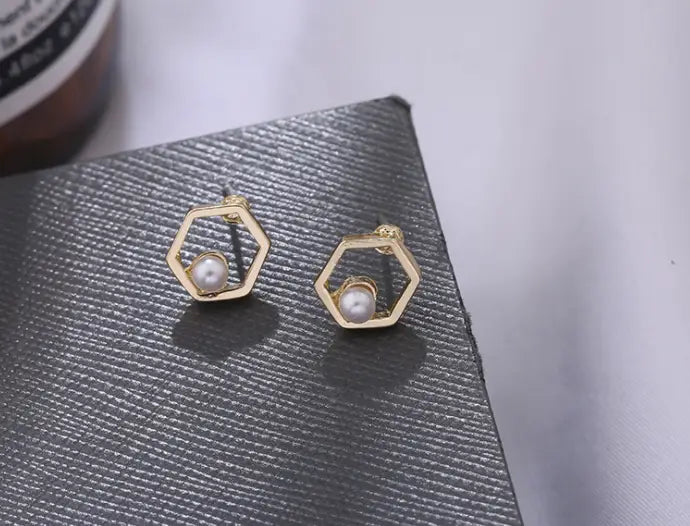 Goldene sechseckige Ohrstecker mit je einer einzelnen weißen Perle im Zentrum, gestaltet als geometrische Goldpfeil- und hohle Quadratohrstecker