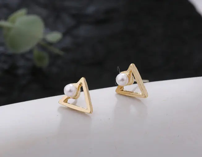 Goldene Dreiecksohrstecker mit je einer einzelnen weißen Perle im Zentrum, Teil der Kollektion der geometrischen Goldpfeil- und hohlen Quadratohrstecker.