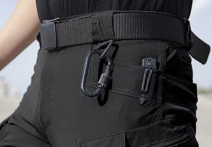 Schwarzer taktischer Gürtel mit Karabiner und Clip, der an der Seiten-Tasche des Sets aus Herren-Taktikfleecejacke und Cargohosen befestigt ist