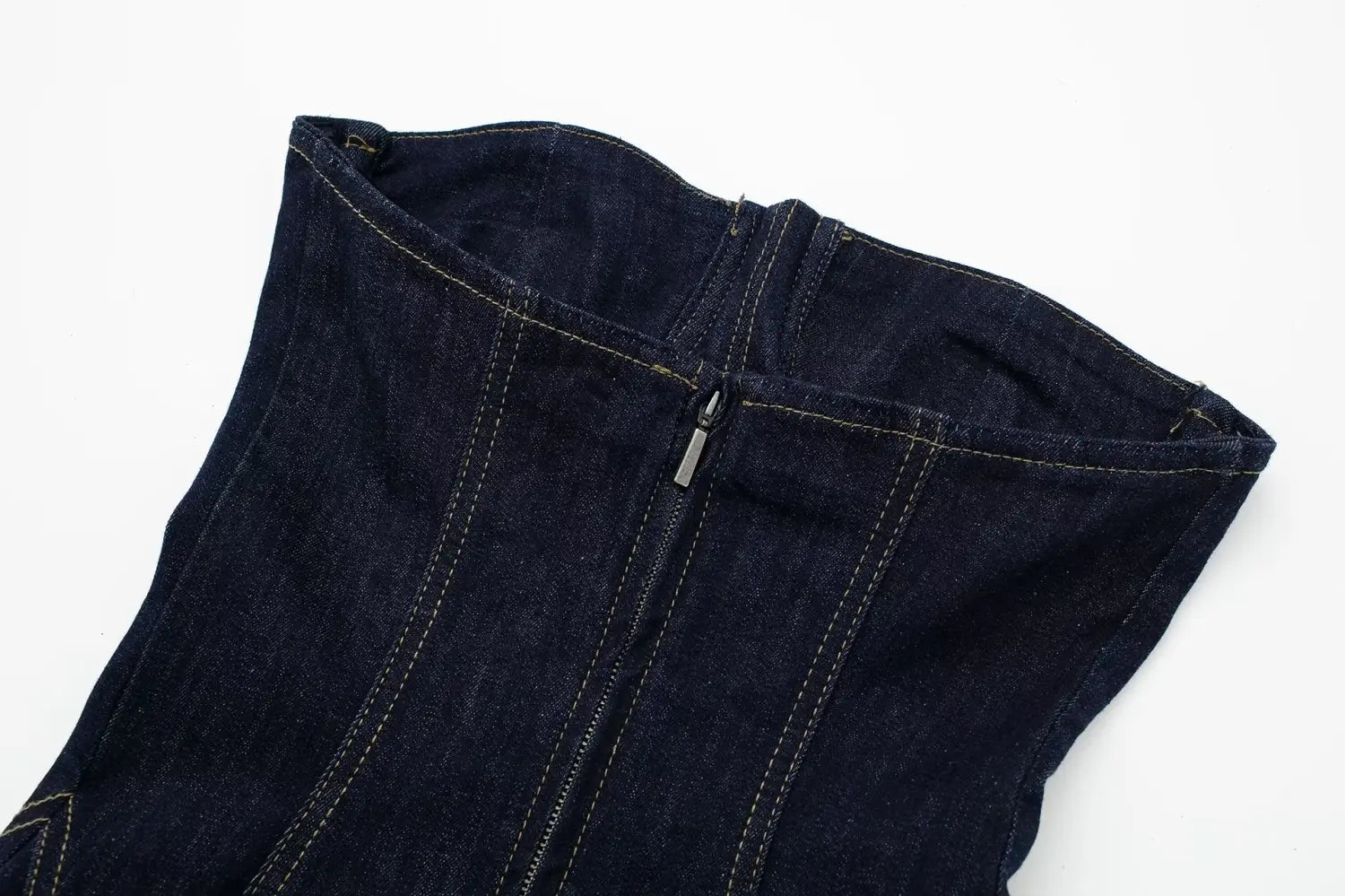 Corset en denim indigo foncé avec surpiqûres visibles et fermeture à glissière centrale sur une robe midi sans bretelles en denim à rayures fantaisie, avec détail de fermeture à glissière.
