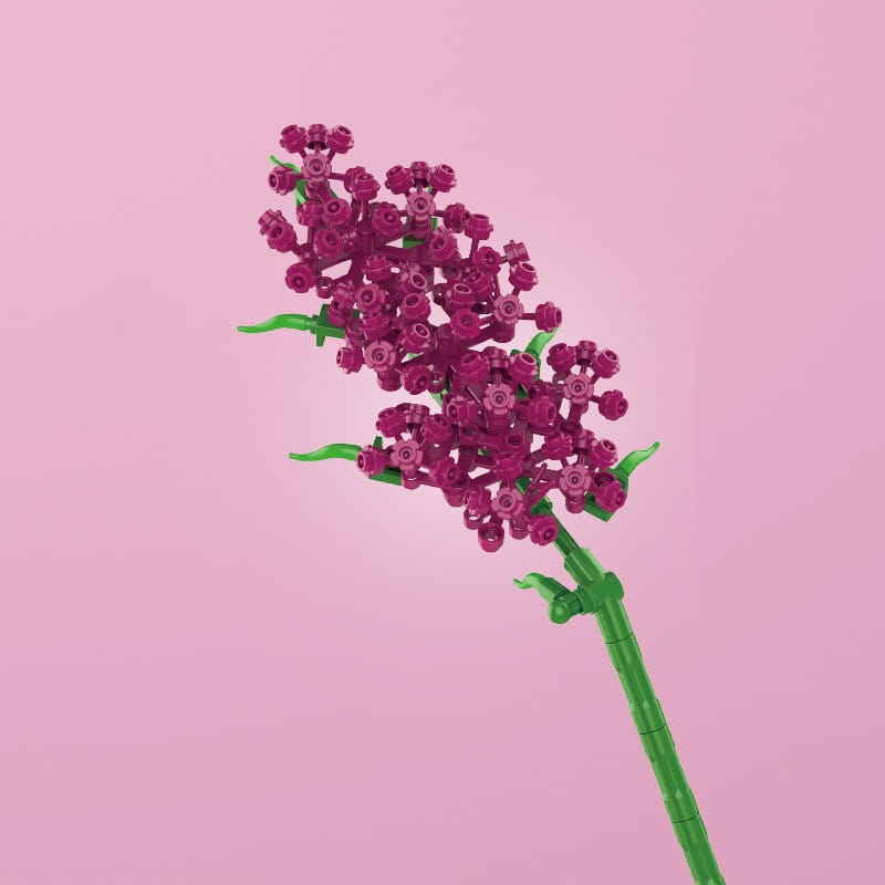 Une fleur en briques Lego magenta vive avec une tige verte et des feuilles, réalisée à partir de briques en plastique imbriquées, dans un bouquet de fleurs en briques, rose bonsaï, jouet.