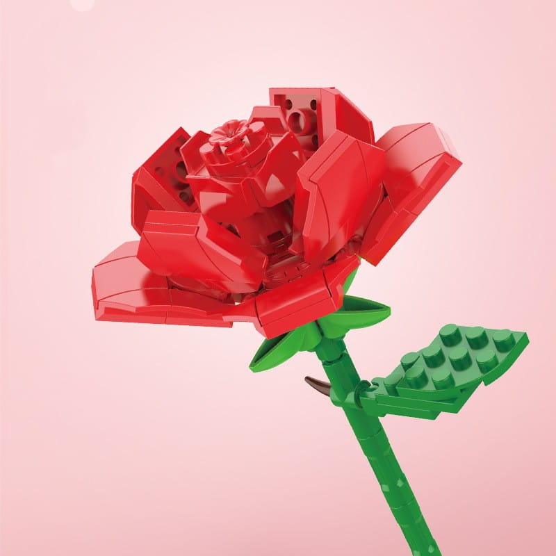 Une rose Lego rouge vive avec une tige verte et une feuille, réalisée à partir de briques en plastique imbriquées, faisant partie d’un bouquet de fleurs en briques, rose bonsaï, jouet.