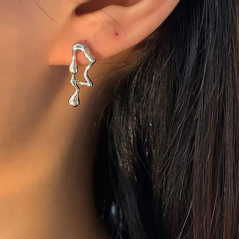 Silberne asymmetrische Ohrstecker aus flüssigem Silberlava mit einer abstrakten, fließenden, tropfenden Ear-Cuff-Gestaltung.