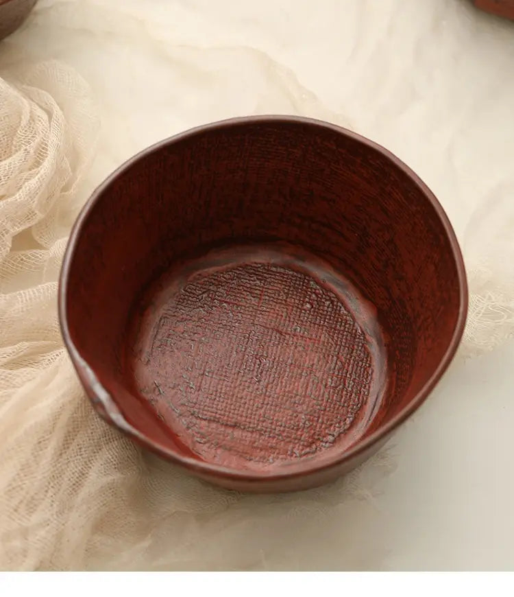 A rustic ceramic rice bowl with a deep reddish-brown textured interior and a smooth slightly uneven rim, handcrafted for serving soup.