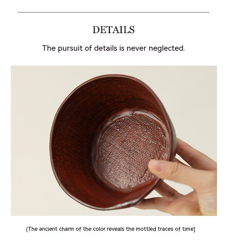 A hand holds a rustic deep reddish brown ceramic rice bowl with a textured interior and subtle mottled patina suitable for soup.