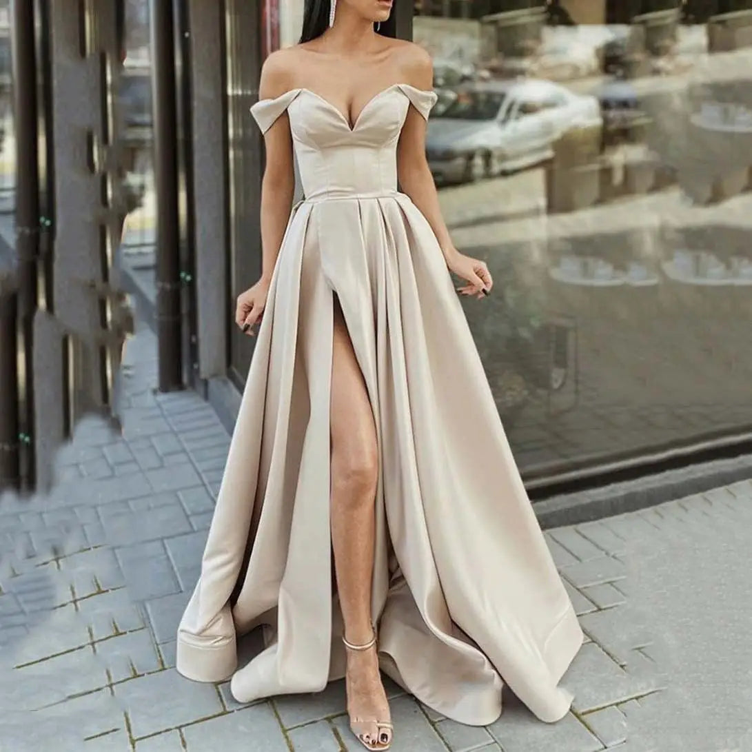 A flowing off the shoulder v neck high slit maxi dress in soft beige satin with a structured bodice.