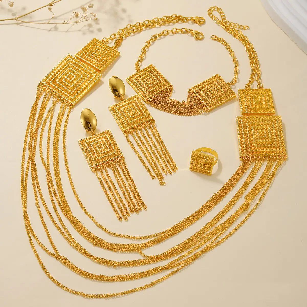 Gold layered tassel necklace and jewelry set featuring gold-toned geometric square pendants and intricate layered chains.