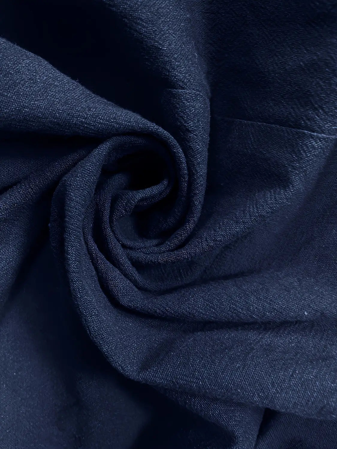 Tejido denim azul oscuro con una trama suave ligeramente texturizada y pliegues naturales en un blazer de lino para mujer, casual y de trabajo.