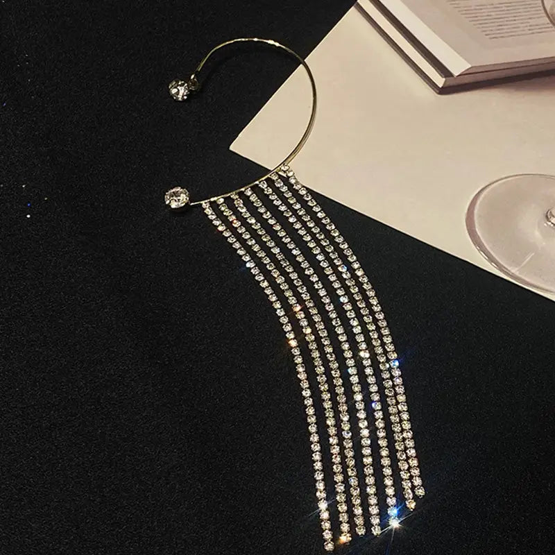 Crystal tassel 14k gold plated long drop earrings feature a shimmering silver crystal ear cuff with cascading rows of rhinestones and a sleek curved design.