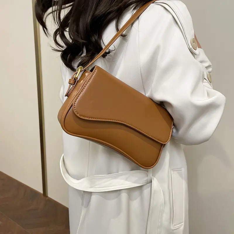 Tan leather messenger bag minimalist crossbody organ bag with a sleek design and gold tone hardware.