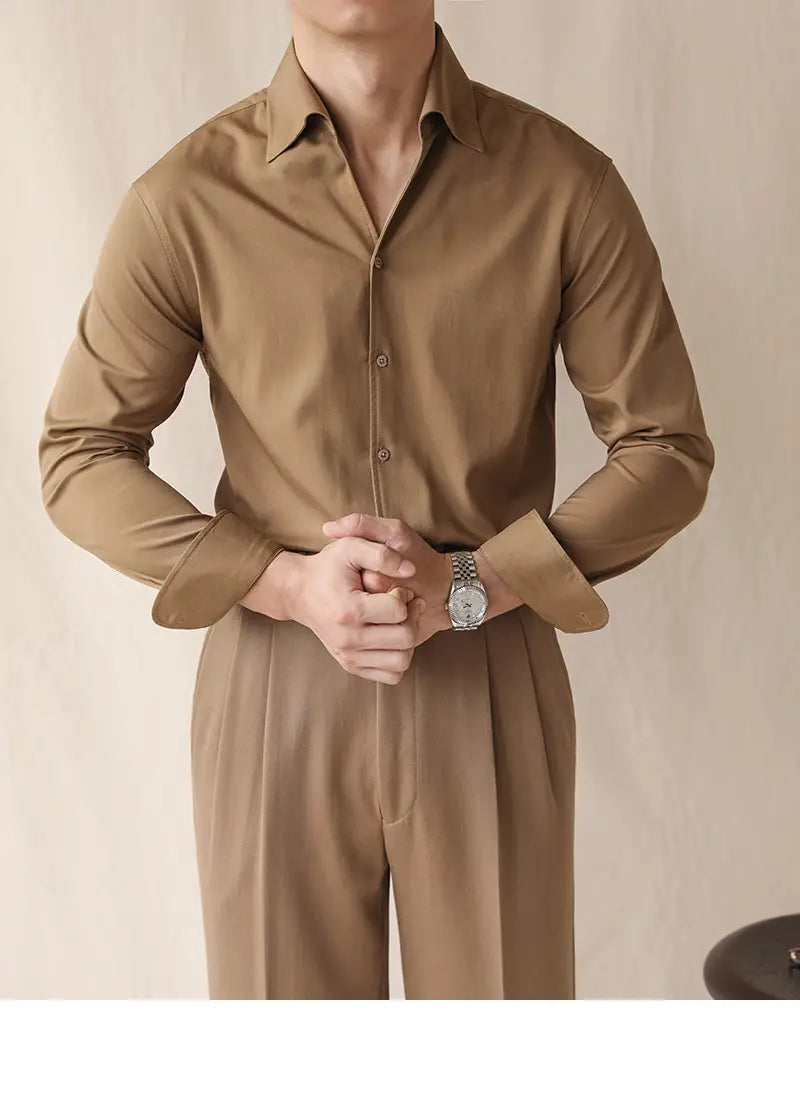 Eine elegante Herrenarmuhr mit silberfarbenem Ton, rundem klassischem Zifferblatt und poliertem Metallband, dargestellt neben einem Herren-Oberteil mit Ein-Kragen aus Satin, langarm im Business-Stil.