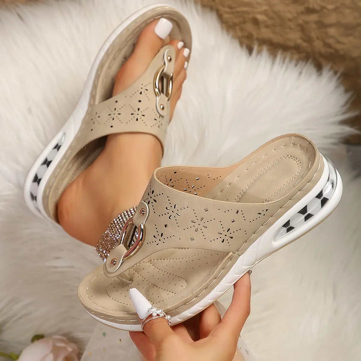 Beige leather air cushion thong sandals with a decorative metallic buckle adorned with rhinestones and perforated detailing on the upper, featuring a white platform sole with black and white checkered accents.
