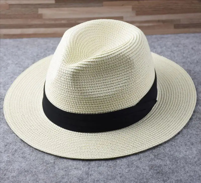 A cream-colored woven straw fedora hat with a wide brim and black ribbon band designed for foldable sun protection for men.