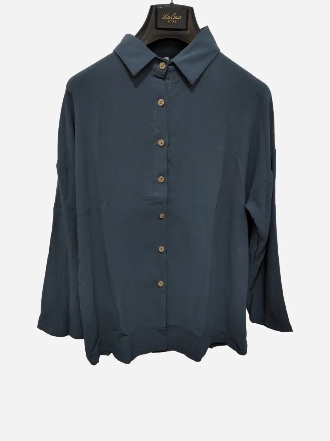 A navy blue women’s relaxed pleated button up shirt with long sleeves rolled up, a classic collar, and matching buttons.