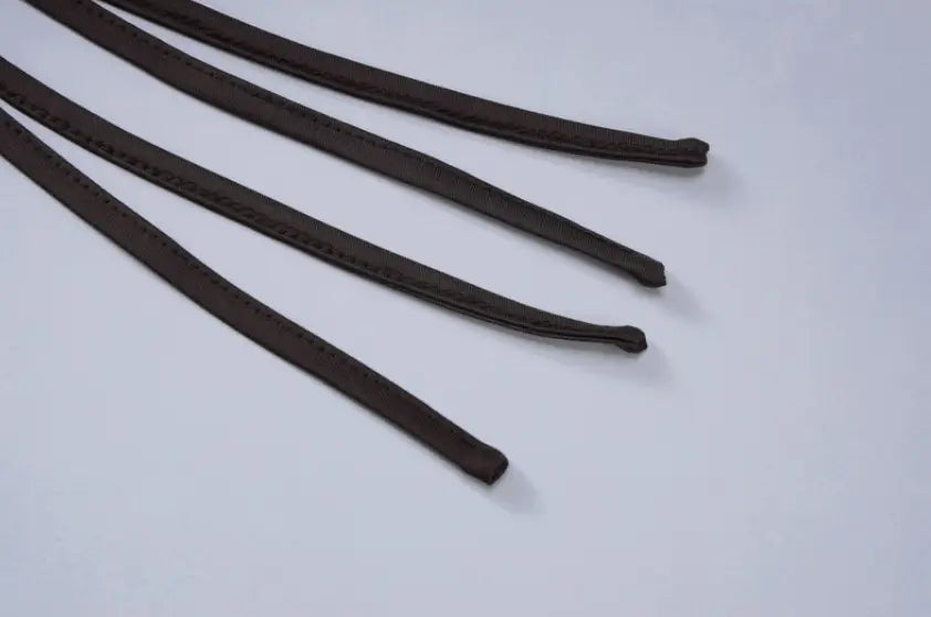 schwarze Gummidichtungen mit glatter, leicht strukturierter Oberfläche und abgerundeten Enden, dargestellt neben einem schulterfreien, gerafften Minikleid mit Taillengürtel