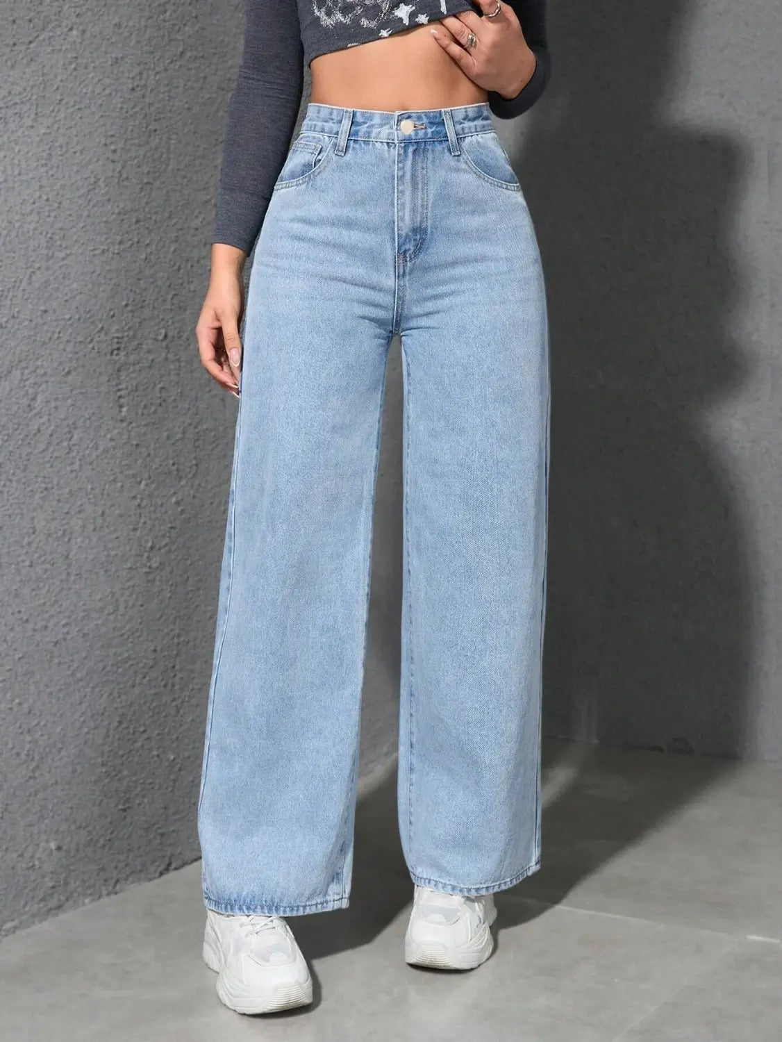 Jean en denim à lavage clair, à taille haute et jambe ample, présentant un design classique à cinq poches et une fermeture boutonnée.