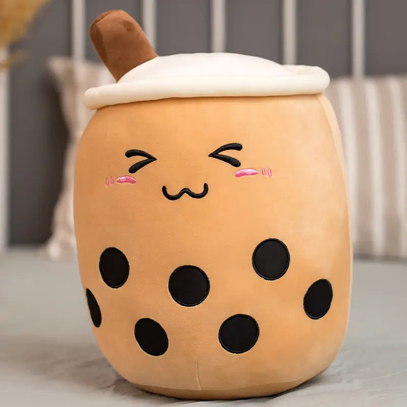 A cute tan plush toy shaped like a boba milk tea cup with black tapioca pearls, a white foam top, and brown straw designed as a soft stuffed hugging pillow.