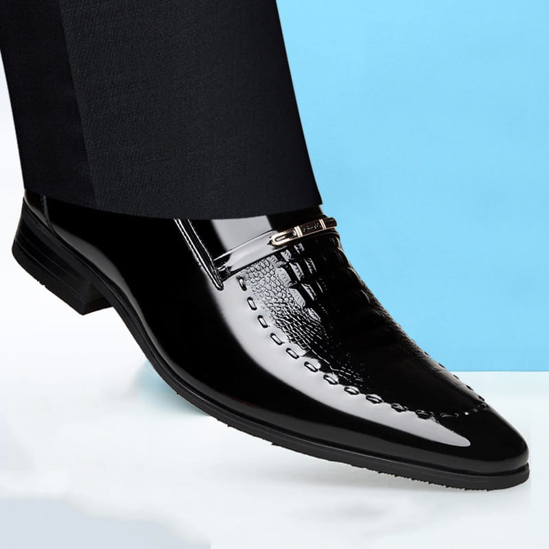 Herren-Slipper aus schwarzem Lackleder mit glänzender Oberfläche, erhabener Krokodilprägung am Vorderkappeneinsatz und dekorativer Ziernaht entlang der Kante.