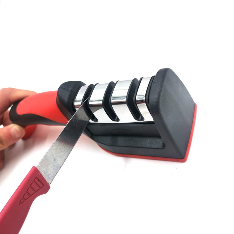 Aiguiseur de couteaux portatif rouge et noir avec trois étapes d’affûtage en acier inoxydable pour une utilisation manuelle des ustensiles de cuisine.