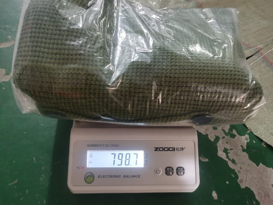 Pull-over en cardigan tricoté pour homme vert, à col montant, fabriqué dans un tissu tissé, enveloppé dans un film plastique transparent sur une balance numérique