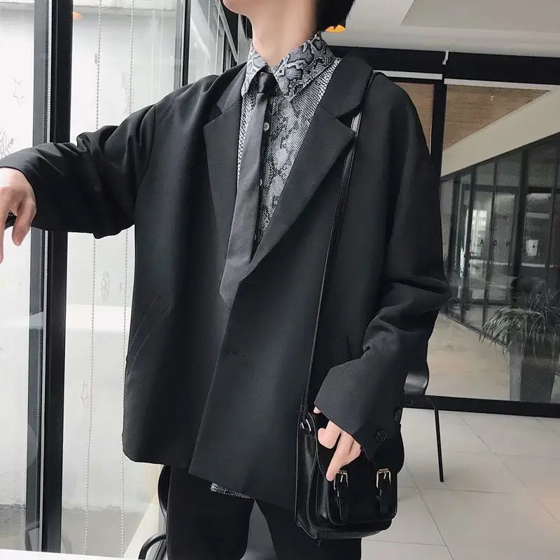 black leather crossbody bag with silver hardware and minimalist design complementing a mens loose casual thin suit jacket.