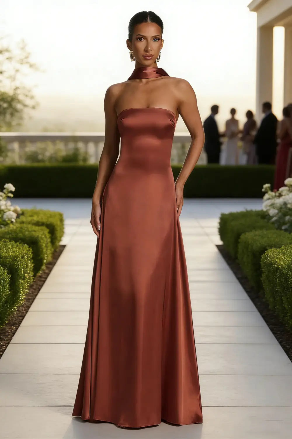Un vestido de noche sin tirantes de satén color óxido, de líneas elegantes, con escote alto drapeado y silueta fluida.