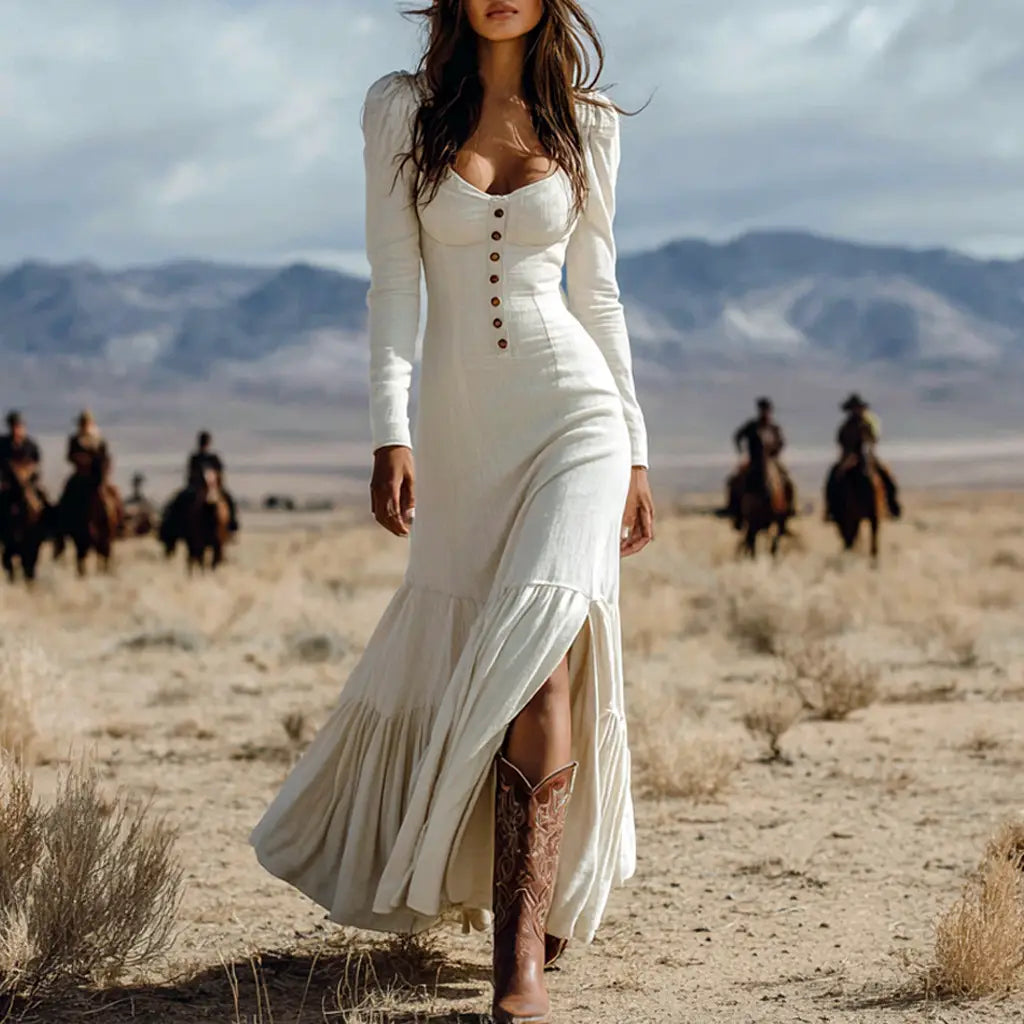 A flowing white long-sleeved retro western buttoned front maxi dress with a buttoned bodice and tiered skirt featuring a high slit.